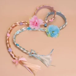 Peruk i prinsessstil med långa flätor och hårband, med en stor flätad blomma i rosa.><noscript><img width=